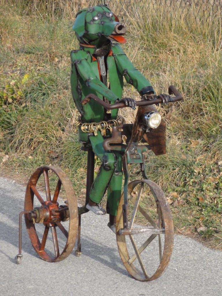 Ce chien vert a été réalisé à partir d'objets agricoles , de roues , d'un socle et de bidons en méatl vert